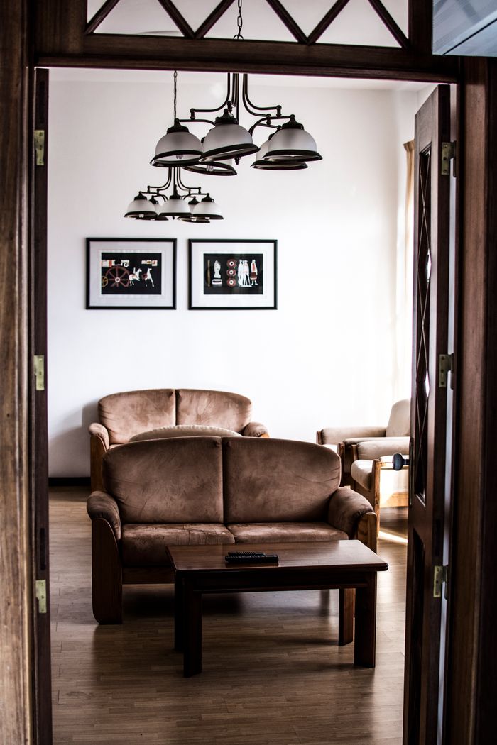 A modern living room with brown furniture, wooden floors, and artistic decor, exuding comfort.